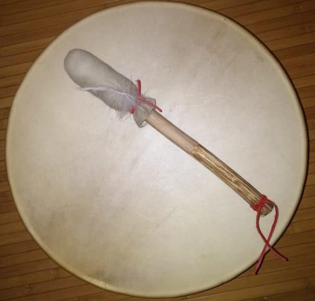 mailloche de tambour chamanique en bois de châtaigner, peau de daim, plume de buse et lacets en cuir rouge.